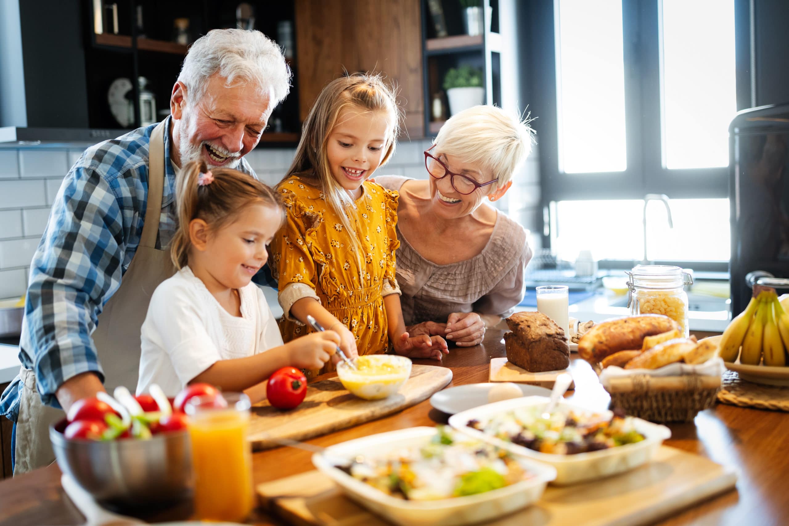 Happy elderly couple having breakfast with their grandchildren at home